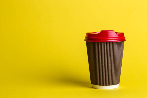coffee to go in a disposable cup on a yellow background, place for text - Foto, afbeelding