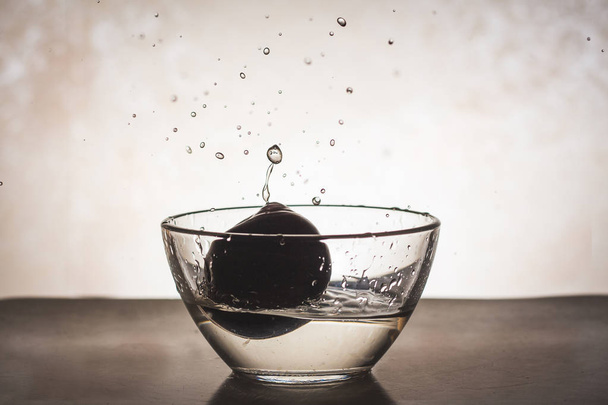 Shot of water waves and splash in a glass with a plum - Valokuva, kuva
