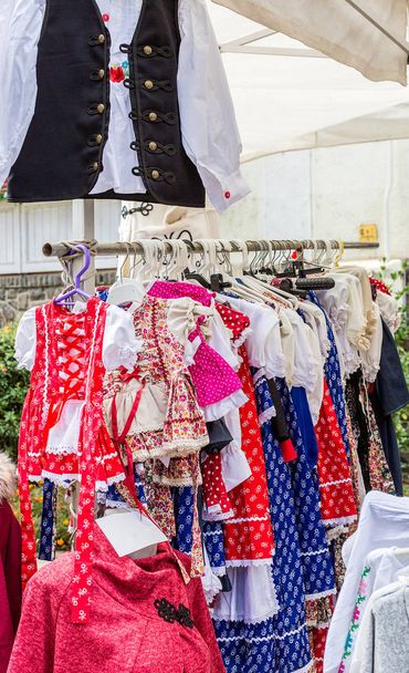 schöne helle ungarische Nationalkleidung, die an Kleiderbügeln im Straßenladen hängt - Foto, Bild