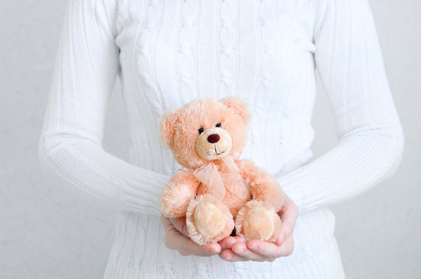 Girl in a white sweater holding a teddy bear. White background. Close-up. - Φωτογραφία, εικόνα
