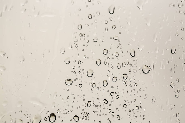 Gotas de lluvia en la superficie de los cristales de ventana con fondo nublado . - Foto, imagen