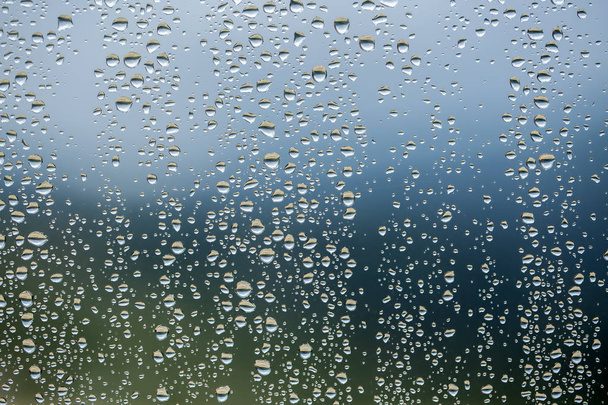 曇った背景の窓ガラス面に雨が降る . - 写真・画像
