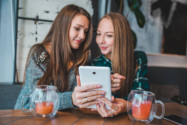 дві жінки говорять в кафе п'ють чай, дивлячись концепцію планшета
 - Фото, зображення