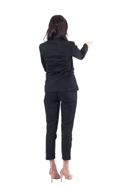 Rückenansicht einer eleganten Geschäftsfrau im schwarzen Anzug, die während der Präsentation auf den Copyspace zeigt. Ganzkörper isoliert auf weißem Hintergrund.  - Foto, Bild