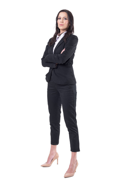Επιτυχημένη αυτοπεποίθηση κομψά γυναικεία business manager στα μαύρο κοστούμι με σταυρωμένα τα χέρια βλέπουν τα φωτογραφικών μηχανών. Γεμάτο σώμα που απομονώνονται σε λευκό φόντο.  - Φωτογραφία, εικόνα