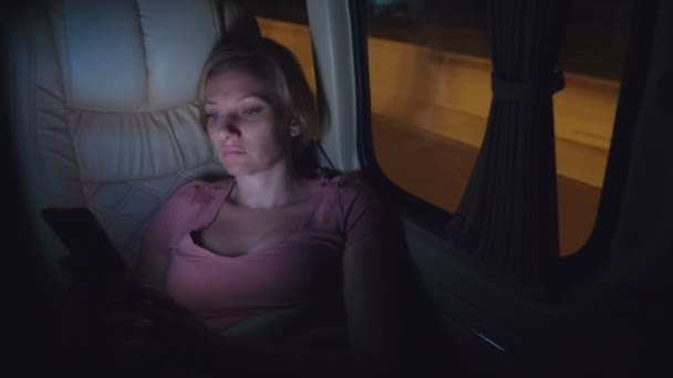 Una donna stanca cavalca la notte sull'autobus, usa il suo telefono
. - Filmati, video