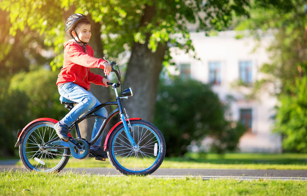 child on a bicycle at asphalt road in summer. Bike in the park - Foto, imagen