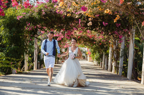 Bellissimi sorridenti giovani sposi che camminano sulla spiaggia, si baciano e si divertono, cerimonia nuziale vicino alle rocce e al mare. Cerimonia nuziale sulla costa di Cipro
 - Foto, immagini