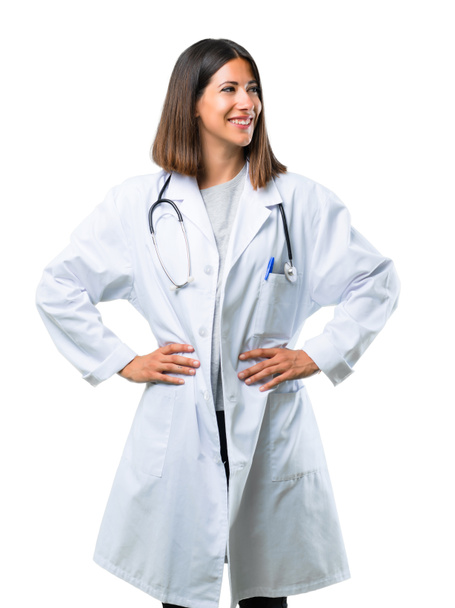 Doctora mujer con estetoscopio posando con los brazos en la cadera y riendo sobre fondo blanco aislado
 - Foto, imagen