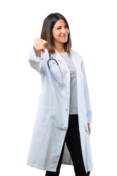 Ärztin mit Stethoskop zeigt mit selbstbewusstem Gesichtsausdruck auf isolierten weißen Hintergrund - Foto, Bild