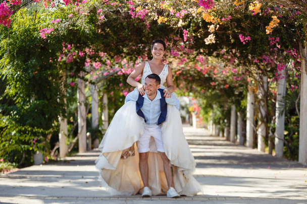 Krásná mladá nevěsta a ženich procházky na pláži, líbání a s fun, svatební obřad v blízkosti skal a moře. Svatební obřad na pobřeží Kypru - Fotografie, Obrázek
