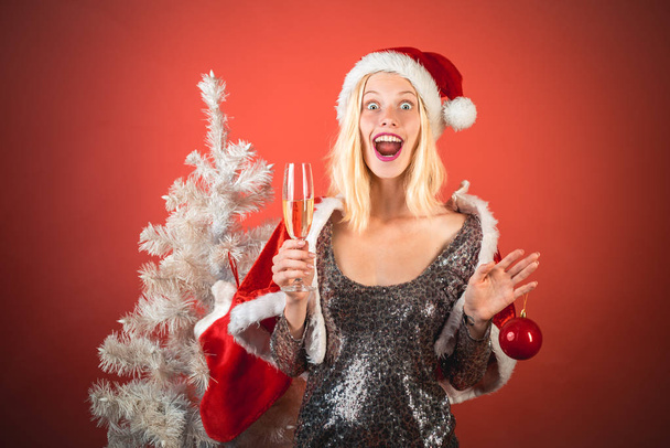 Smiling woman decorating Christmas tree at red Background. Friendly and joy. Christmas woman. Young woman wink. New year gift. Happy new year - Φωτογραφία, εικόνα
