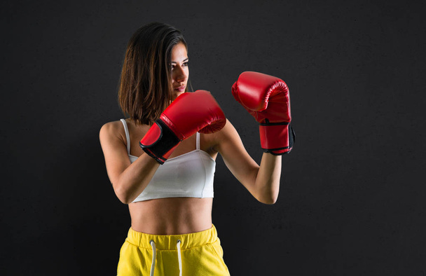 Sportlerin mit Boxhandschuhen auf schwarzem Hintergrund - Foto, Bild