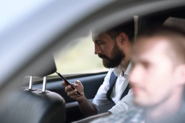close up.businessman reading SMS on his smartphone, sitting in the car - Фото, изображение