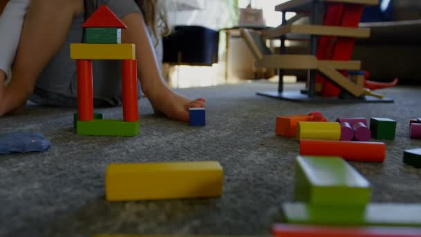 Cute little girl playing with building blocks on the floor of the living room at home. - Video