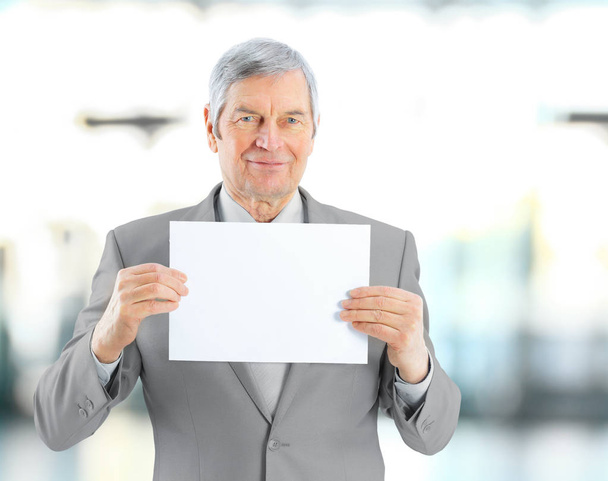 closeup.Mature businessman showing a blank sheet. isolated on blurred background - Foto, Imagem