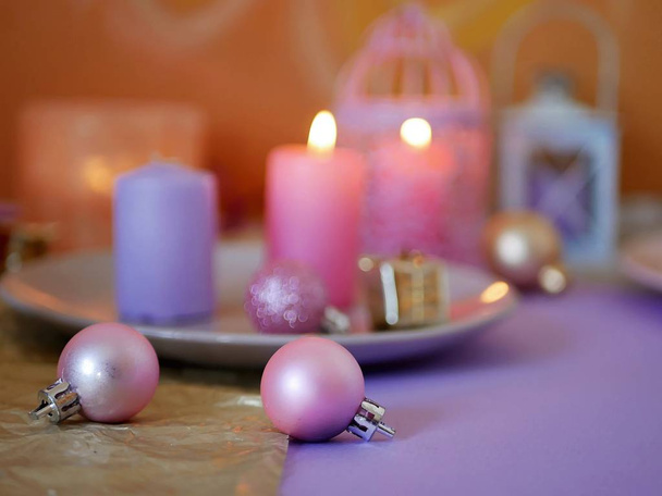 Decoratieve compositie in een roze kleur van het branden van kaarsen, decoratieve lantaarns, oosterse snoepjes op gerechten, Christmas decor, ballen op een lichte zilveren achtergrond, romantische sfeer, seizoensgebonden wintervakantie - Foto, afbeelding