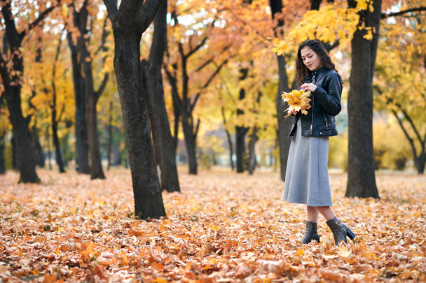 Hübsche Frau posiert mit Ahornblättern im Herbstpark. schöne Landschaft zur Herbstzeit. - Foto, Bild