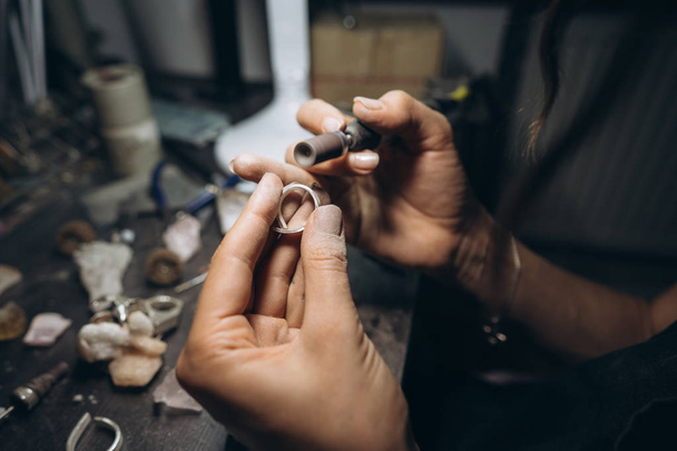 Девушка мастер обрабатывает металлическую пластину в домашней мастерской
 - Фото, изображение
