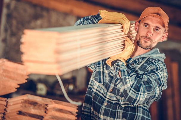 Appaltatore di legname caucasico sulla trentina con tavole di legno sulla spalla. Tema della costruzione
. - Foto, immagini
