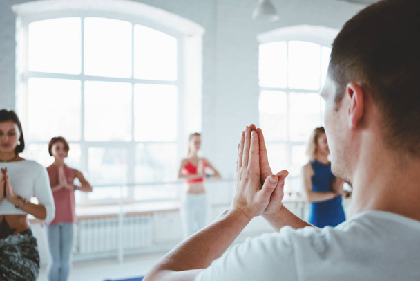 Dospělý muž jóga instruktor vlaky a vyučovací skupiny žen jóga cvičení pro udržení zdravotní péči v bílých třídě. Rozmazané pozadí - Fotografie, Obrázek