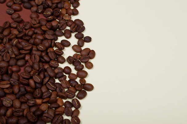 Scattered roasted coffee beans on double-toned beige and brown background. Copy space. - Photo, Image