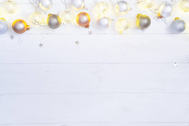 Weihnachten und Neujahr Holzhintergrund mit Licht festlich goldene Dekoration Girlande mit Weihnachtskugeln und Spielzeug auf weißem Holzhintergrund, Draufsicht - Foto, Bild