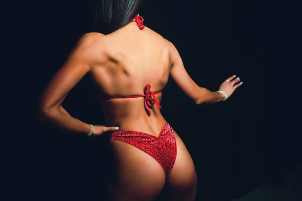 мускулистая атлетичная молодая женщина в цветном купальнике на черном фоне. Фитнес. Мышечное тело. Торс. Мышцы живота
 - Фото, изображение