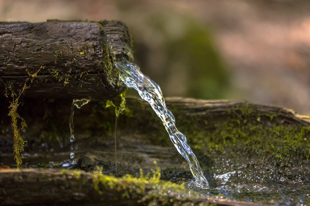 Água da montanha brota da sarjeta de madeira do riacho rochoso
 - Foto, Imagem