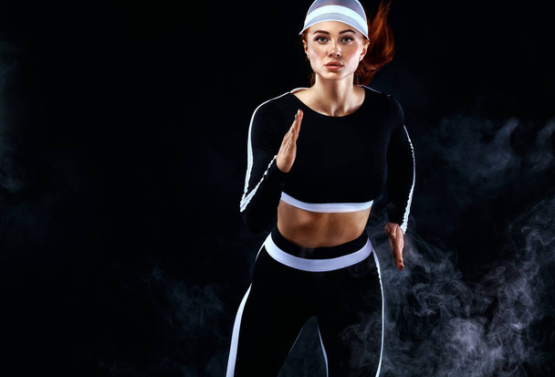 Sprinter mulher atlética forte, correndo em fundo preto vestindo no sportswear. Aptidão e motivação desportiva. Conceito de corredor com espaço de cópia
. - Foto, Imagem