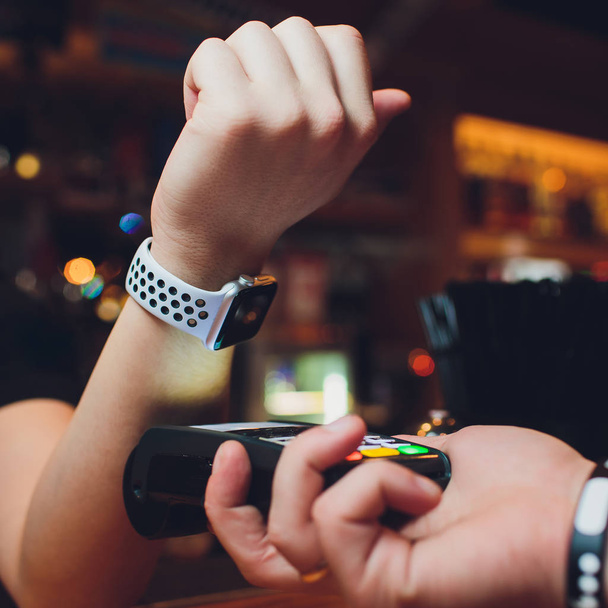 Cropped image of female customer paying through smart watch at bar. - Foto, immagini