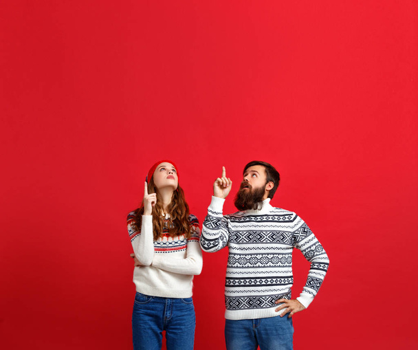 happy cheerful couple man and woman in christmas hats on red backgroun - Foto, Imagen