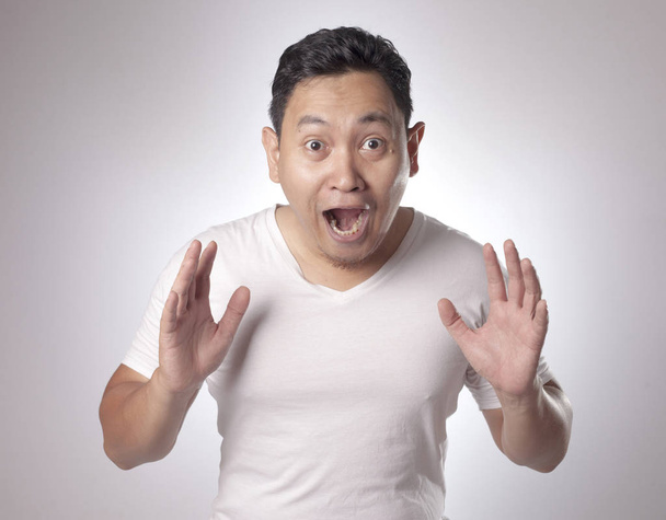 Portrait of funny young Asian men shows winning gesture, shocked surprised with open mouth. Hands raised above - Photo, Image