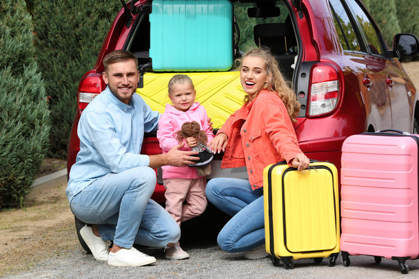 Young family with suitcases near car trunk outdoors - Zdjęcie, obraz