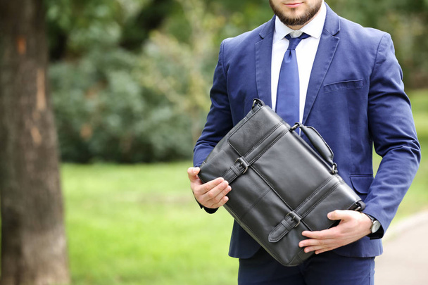 Бізнесмен з чорним портфелем в руках на відкритому повітрі. Простір для тексту
 - Фото, зображення