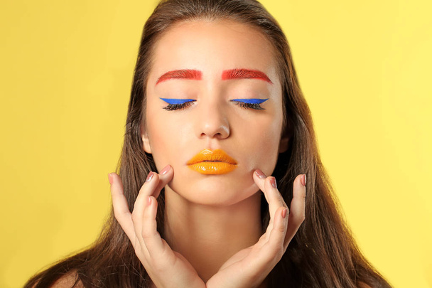 Young woman with dyed eyebrows and creative makeup on color background - Фото, зображення