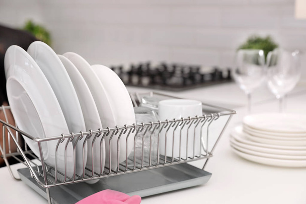 Dish drainer with clean dinnerware on table in kitchen - Photo, image