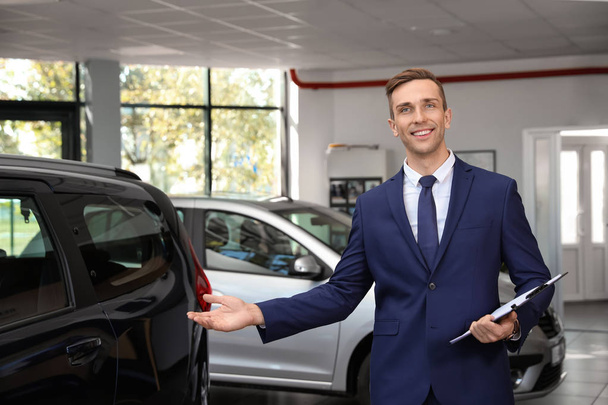 Portrait of young car salesman in dealership - Foto, Imagen