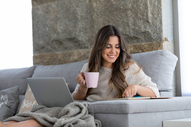 Красивая молодая женщина отдыхает дома на ноутбуке
 - Фото, изображение