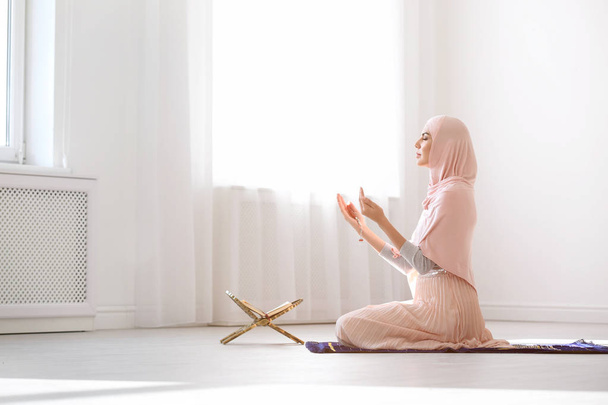 Muslim woman in hijab praying on mat indoors - Foto, Bild