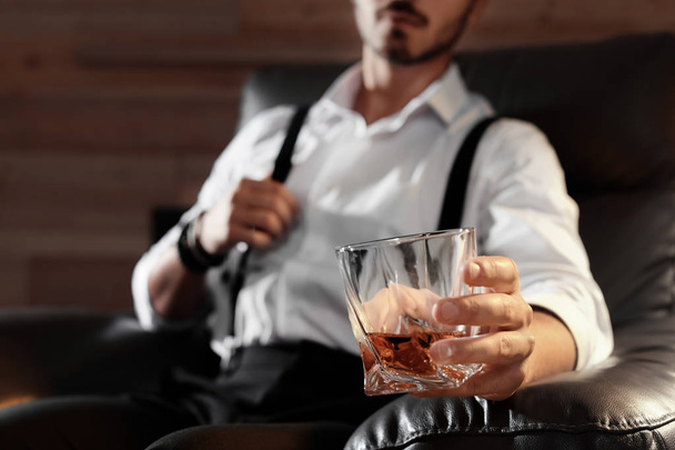 Man with glass of whiskey sitting in armchair, closeup. Space for text - Foto, afbeelding