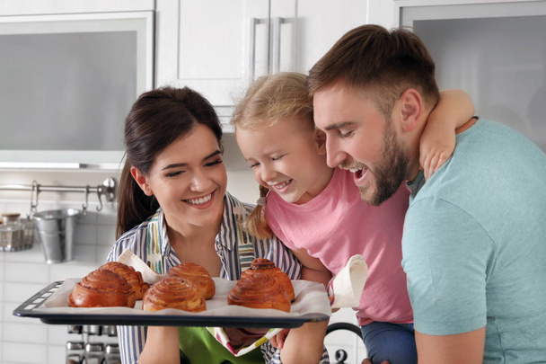 Beautiful woman treating her family with freshly oven baked buns in kitchen - Foto, afbeelding