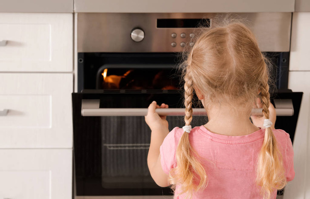 Little girl opening oven while baking in kitchen - Photo, image