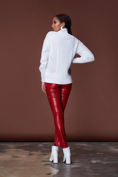 Sexy beautiful woman fashion glamour model brunette hair makeup wear knitted sweater red lather trousers clothes for every day casual party style jewelry date walk girlfriend skinny body shape studio. - Fotoğraf, Görsel