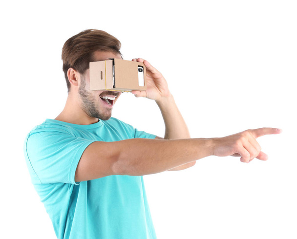 Young man using cardboard virtual reality headset, isolated on white - 写真・画像