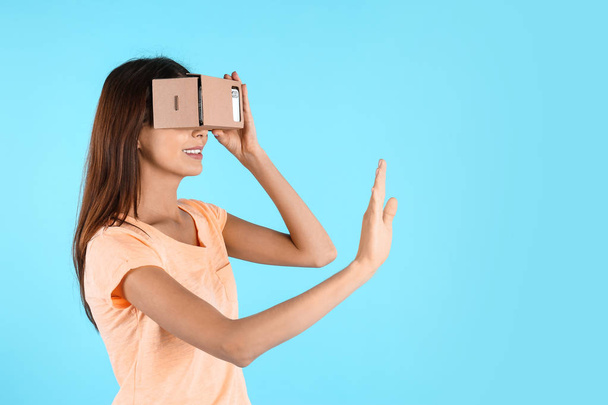 若い女性一色の背景に段ボールの仮想現実のヘッドセットを使用しています。テキストのためのスペース - 写真・画像