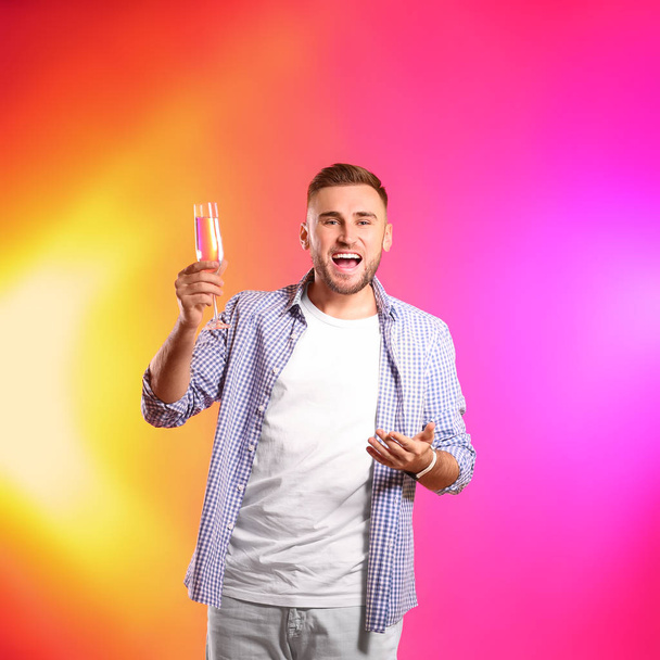 Portrait d'homme heureux avec champagne en verre sur fond de couleur
 - Photo, image