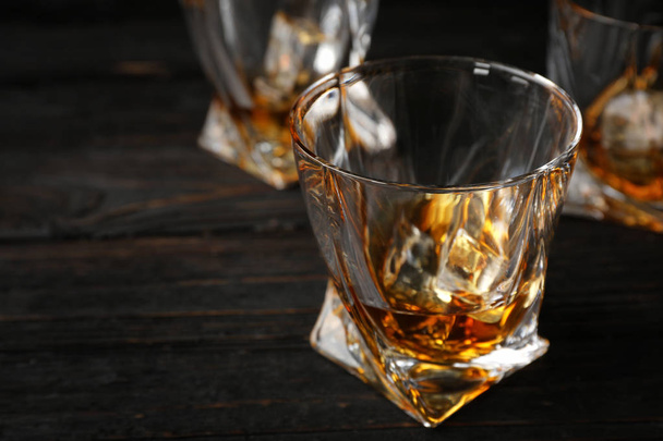 Kultainen viski lasissa jääkuutioilla puupöydällä. Tekstitila
 - Valokuva, kuva