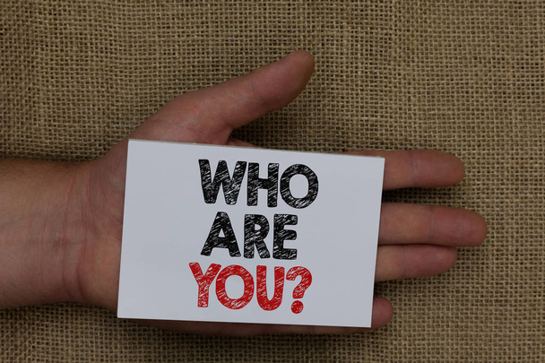 Пишу записку с вопросом "Кто ты?". Идентифицировать себя описание личных характеристик человека, держа белую страницу с черно-красным цветом текстов на мешке
. - Фото, изображение