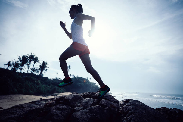Ženská stezka běžec běží na vrcholu skalnaté hory na přímořské - Fotografie, Obrázek